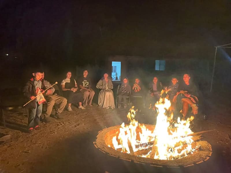 Members sitting around a campfire at night during the annual camp.