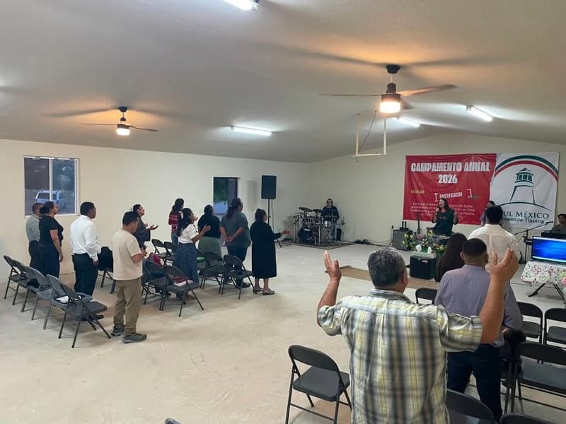 Members worshiping with raised hands in the meeting hall during the annual camp.