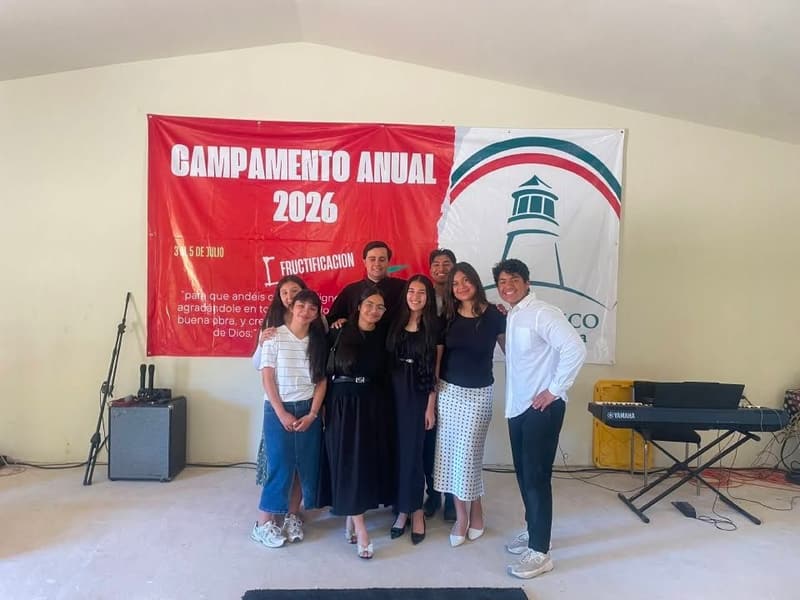 A group of young people standing together in front of the 2026 annual camp banner.