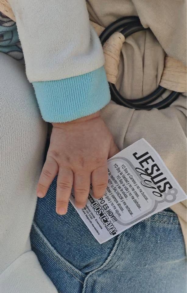 A hand holding a small printed leaflet that says Jesús.